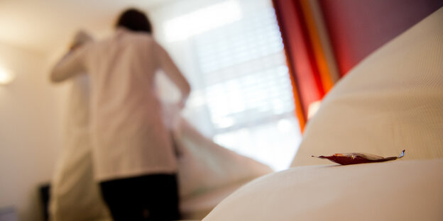 Ein Mensch macht Betten in einem Hotelzimmer Ein Mensch macht Betten in einem Hotelzimmer