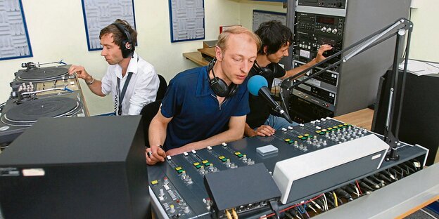 Im Studio des alternativen Senders FSK. Drei Männer bedienen jeweils unterschiedliche Geräte Im Studio des alternativen Senders FSK. Drei Männer bedienen jeweils unterschiedliche Geräte