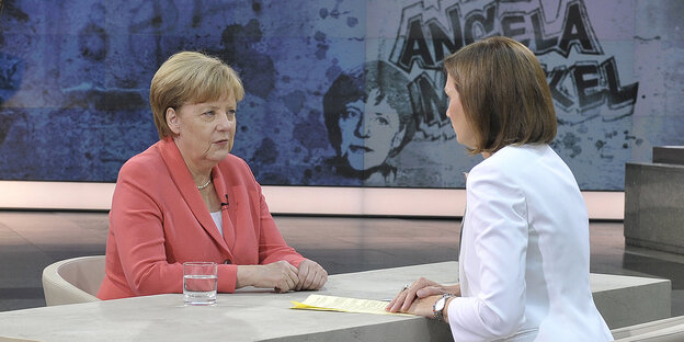 Zwei Frauen sitzen einander gegenüber. Es sind Angela Merkel und die Journalistin Bettina Schausten Zwei Frauen sitzen einander gegenüber. Es sind Angela Merkel und die Journalistin Bettina Schausten