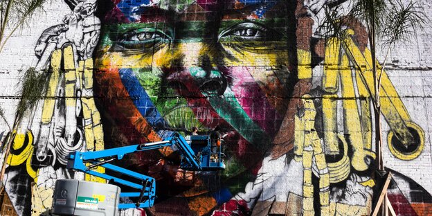 Riesiges Wand-Graffiti mit einem buntbemalten Gesicht Riesiges Wand-Graffiti mit einem buntbemalten Gesicht
