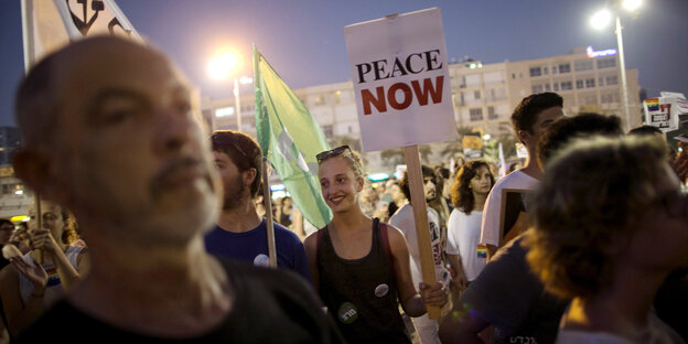 Eine Demo, auf der jemand ein Schild mit der Aufschrift "Peace Now" hochhält Eine Demo, auf der jemand ein Schild mit der Aufschrift "Peace Now" hochhält