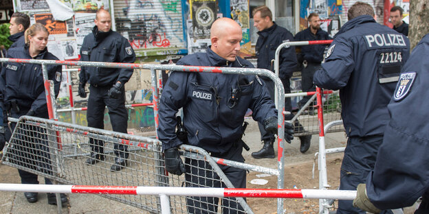 Polizisten tragen Absperrgitter weg Polizisten tragen Absperrgitter weg