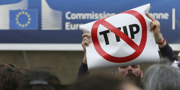 Ein Mann hält ein Anti-TTIP-Plakat hoch Ein Mann hält ein Anti-TTIP-Plakat hoch
