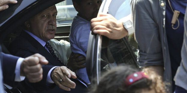 Recep Tayyip Erdogan sitzt in einem Auto, die Tür ist offen und er deutet mit der Hand hinaus Recep Tayyip Erdogan sitzt in einem Auto, die Tür ist offen und er deutet mit der Hand hinaus