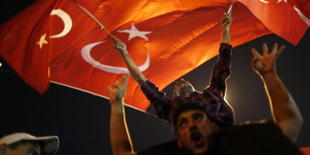 Männer schwenken türkische Flaggen. Es ist dunkel Männer schwenken türkische Flaggen. Es ist dunkel