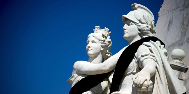 Zwei Statuen mit schwarzen Schärpen vor blauem Himmel Zwei Statuen mit schwarzen Schärpen vor blauem Himmel