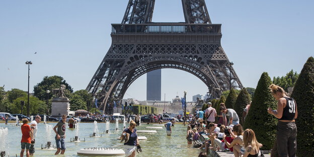 Ein Sommertag: Vor dem Eiffelturm in Paris planschen Menschen im Wasser oder halten ihre Füße hinein Ein Sommertag: Vor dem Eiffelturm in Paris planschen Menschen im Wasser oder halten ihre Füße hinein