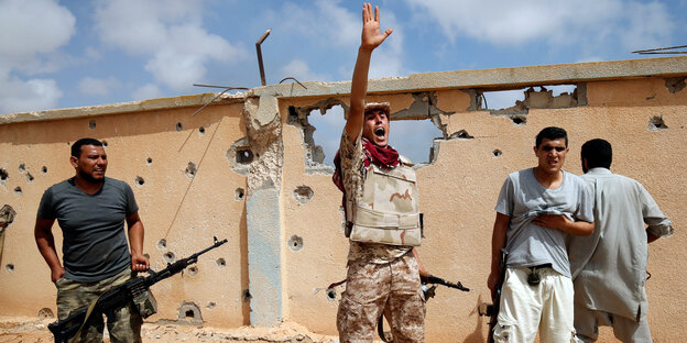 Libyscher Kämpfer vor einer zerschossenen mauer in Sirte Libyscher Kämpfer vor einer zerschossenen mauer in Sirte