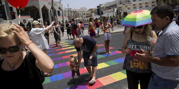 Menschen laufen bei der jährlichen Gay Pride in Tel Aviv über einen regenbogenfarbenen Zebrastreifen Menschen laufen bei der jährlichen Gay Pride in Tel Aviv über einen regenbogenfarbenen Zebrastreifen
