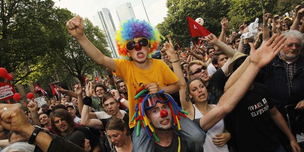 Menschen demonstrieren, einige als Clowns verkleidet Menschen demonstrieren, einige als Clowns verkleidet