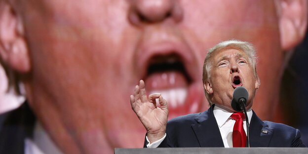 Donald Trump mit aufgerissenem Mund vor einer Leinwand, die sein Gesicht noch einmal zeigt Donald Trump mit aufgerissenem Mund vor einer Leinwand, die sein Gesicht noch einmal zeigt