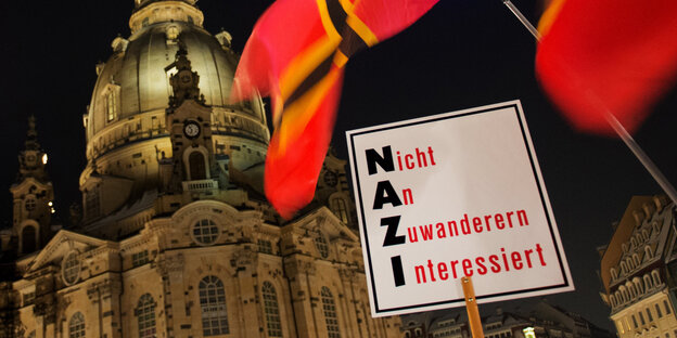 Vor der Frauenkirche in Dresden wird ein Schild hochgehalten auf dem steht „Nicht an Zuwanderern interessiert“. Die Anfangsbuchstaben der Worte sind gefettet Vor der Frauenkirche in Dresden wird ein Schild hochgehalten auf dem steht „Nicht an Zuwanderern interessiert“. Die Anfangsbuchstaben der Worte sind gefettet