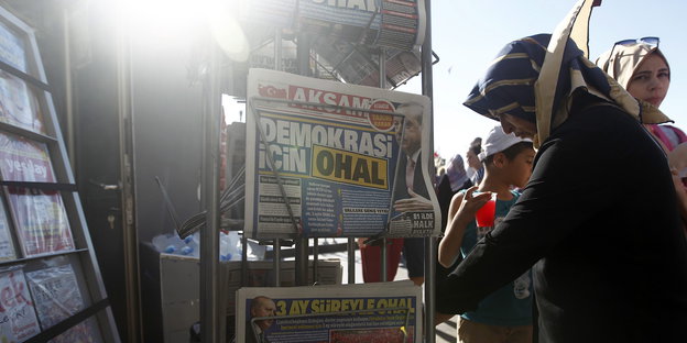 Eine Frau steht neben einem Ständer mit türkischen Zeitungen