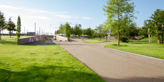 Eine flache grüne Parklandschaft, durchzogen von einem geraden Weg Eine flache grüne Parklandschaft, durchzogen von einem geraden Weg