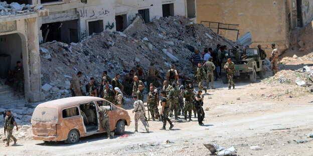 Syrische Regierungssoldaten vor einem zerstörten Gebäude neben einem Kleinbus Syrische Regierungssoldaten vor einem zerstörten Gebäude neben einem Kleinbus