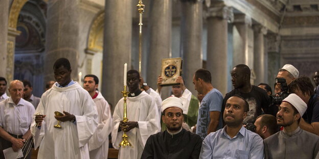 Messdiener laufen durch die Kirche, in der ersten Reihe sitzen Muslime Messdiener laufen durch die Kirche, in der ersten Reihe sitzen Muslime