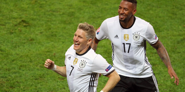 Zwei Fußballer laufen über den Rasen. Es sind Bastian Schweinsteiger und Jérôme Boateng Zwei Fußballer laufen über den Rasen. Es sind Bastian Schweinsteiger und Jérôme Boateng
