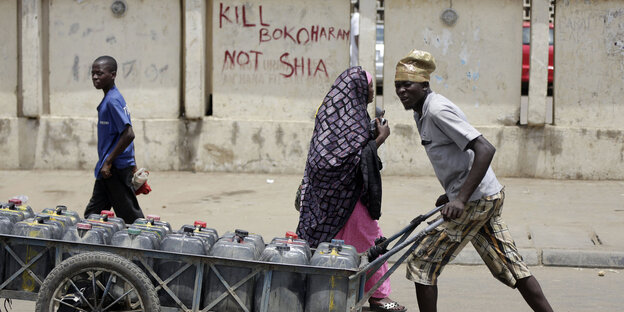Ein Mann schiebt einen Karren vor einer Wand mit der Aufschrift: "Kill Boko Haram not Shia" Ein Mann schiebt einen Karren vor einer Wand mit der Aufschrift: "Kill Boko Haram not Shia"