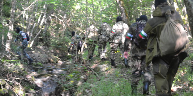 Eine Gruppe Männer in Flecktarn-Uniformen läuft in einer Reihe durch einen Wald Eine Gruppe Männer in Flecktarn-Uniformen läuft in einer Reihe durch einen Wald