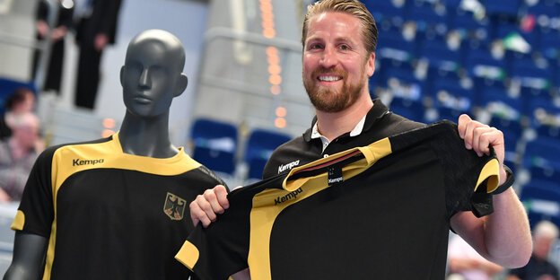 Ein Mann, Oliver Roggisch, hält ein Trikot in der Hand Ein Mann, Oliver Roggisch, hält ein Trikot in der Hand
