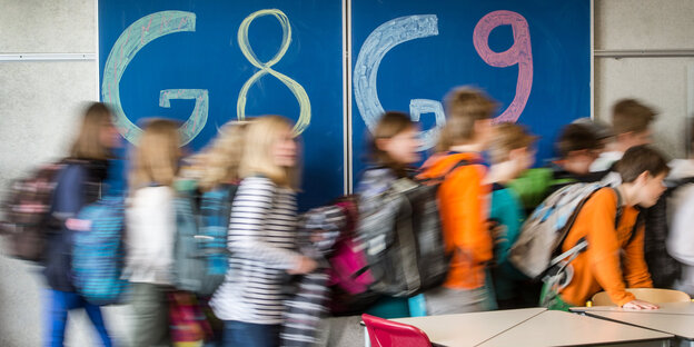 Schüler laufen vor einer TAfel vorbei auf der G8 und G9 steht Schüler laufen vor einer TAfel vorbei auf der G8 und G9 steht