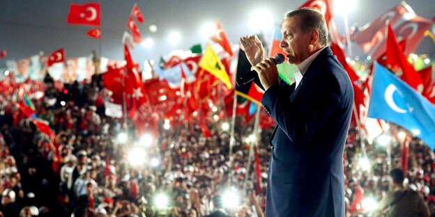 Erdoğan steht mit einem Mikro in der Hand vor einer Menschenmenge Erdoğan steht mit einem Mikro in der Hand vor einer Menschenmenge