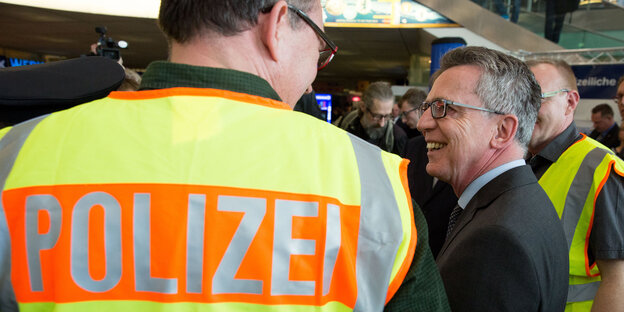 Der Innenminister und ein Polizeibeamter lächeln sich an Der Innenminister und ein Polizeibeamter lächeln sich an