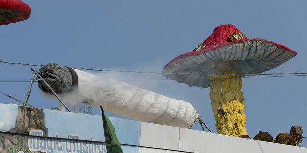 Modelle eines riesigen Pilzes und eines ebensogroßen rauchenden Joint auf einem Hausdach Modelle eines riesigen Pilzes und eines ebensogroßen rauchenden Joint auf einem Hausdach