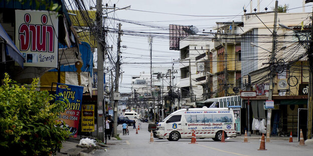Eine leere, abgesperrte Straße in einer thailändischen Stadt, ein weißer Lieferwagen steht in der Mitte Eine leere, abgesperrte Straße in einer thailändischen Stadt, ein weißer Lieferwagen steht in der Mitte