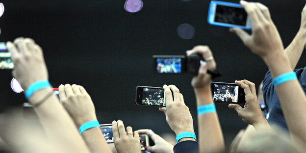 Viele Menschen halten ihre Smartphones in die Höhe und filmen Viele Menschen halten ihre Smartphones in die Höhe und filmen
