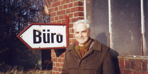 J.J. Voskuil neben einem Schild, auf dem Büro steht J.J. Voskuil neben einem Schild, auf dem Büro steht