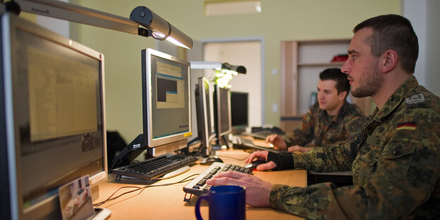 Zwei Soldaten der Bundeswehr blicken auf Computerbildschirme. Zwei Soldaten der Bundeswehr blicken auf Computerbildschirme.