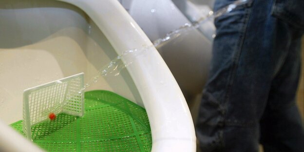 Urinal mit einem kleinen Fußballtor Urinal mit einem kleinen Fußballtor