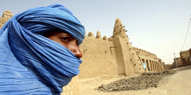 Ein Tuareg-Mann mit blauem Schleier steht vor einem der Mausoleen von Timbuktu Ein Tuareg-Mann mit blauem Schleier steht vor einem der Mausoleen von Timbuktu
