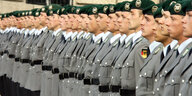 Rekruten in Uniformen und mit Baretten stehen in einer Reihe