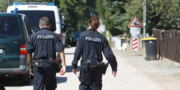 Zwei PolizistInnen gehen eine Straße entlang Zwei PolizistInnen gehen eine Straße entlang