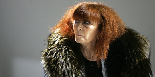 Eine ältere Frau mit roten Haaren und einem enormen Pelzkragen am schwarzen Mantel Eine ältere Frau mit roten Haaren und einem enormen Pelzkragen am schwarzen Mantel