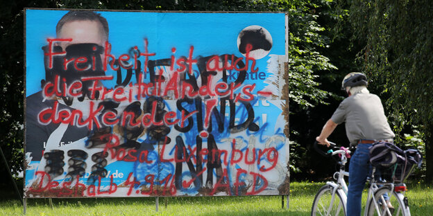 Ein Radfahrer vor einem durchgekritzeltem Poster der AfD Ein Radfahrer vor einem durchgekritzeltem Poster der AfD