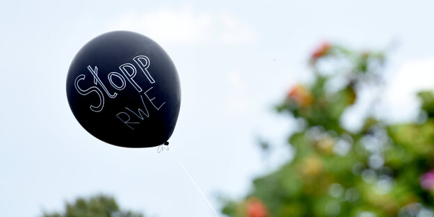 Ein schwarzer Luftballon, auf dem „Stopp RWE“ steht Ein schwarzer Luftballon, auf dem „Stopp RWE“ steht