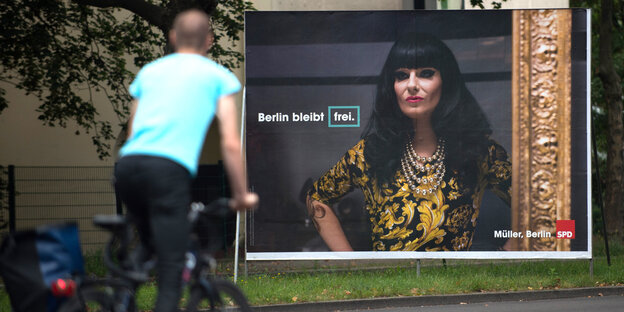 Ein Radfahrer fährt an einem Wahlplakat der Berliner SPD vorbei. Darauf ist zu sehen: Die Drag Queen Nina Queer und die Aufschrift „Berlin bleibt frei“ Ein Radfahrer fährt an einem Wahlplakat der Berliner SPD vorbei. Darauf ist zu sehen: Die Drag Queen Nina Queer und die Aufschrift „Berlin bleibt frei“