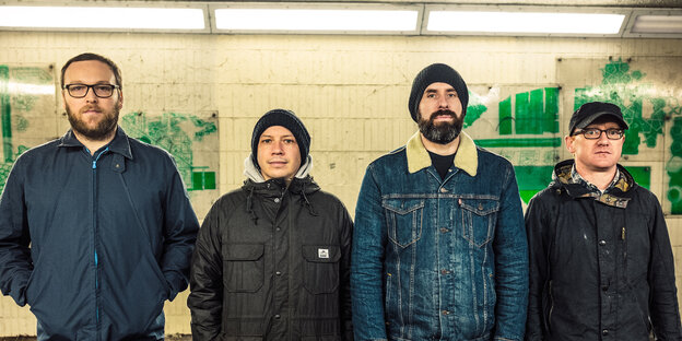 Die schottische Band Mogwai, vier Männer, steht in dicken Jacken in einem U-Bahnhof Die schottische Band Mogwai, vier Männer, steht in dicken Jacken in einem U-Bahnhof