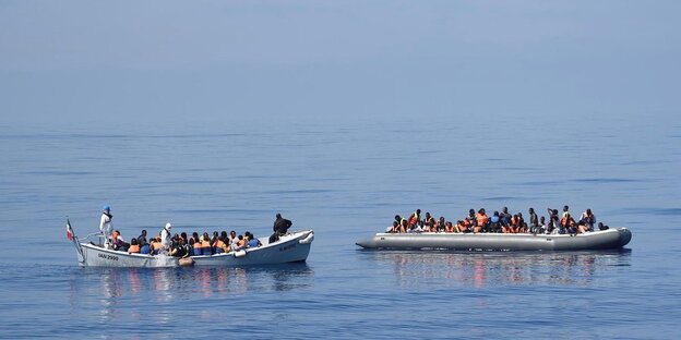 Zwei voll besetzte Boote im Wasser Zwei voll besetzte Boote im Wasser