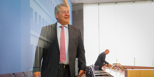 Sigmar Gabriel, durch eine reflektierende Glasscheibe fotografiert, lacht höhnisch Sigmar Gabriel, durch eine reflektierende Glasscheibe fotografiert, lacht höhnisch