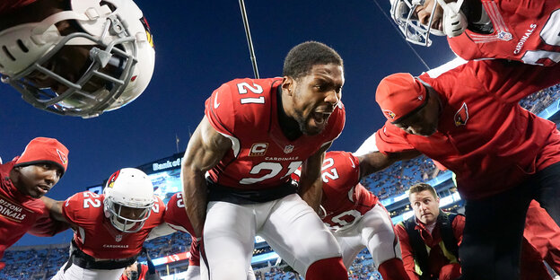 American-Football-Spieler bilden einen Kreis, in der Mitte steht einer und brüllt rum American-Football-Spieler bilden einen Kreis, in der Mitte steht einer und brüllt rum