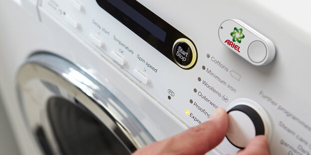 An einer Waschmaschine klebt ein Dash-Button mit dem „Ariel“-Logo An einer Waschmaschine klebt ein Dash-Button mit dem „Ariel“-Logo