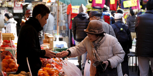 Eine Frau bezahlt an einem Marktstand Eine Frau bezahlt an einem Marktstand