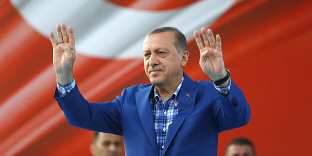 Erdogan mit zum Gruß erhobenen Händen vor einer großen Türkei-Flagge Erdogan mit zum Gruß erhobenen Händen vor einer großen Türkei-Flagge