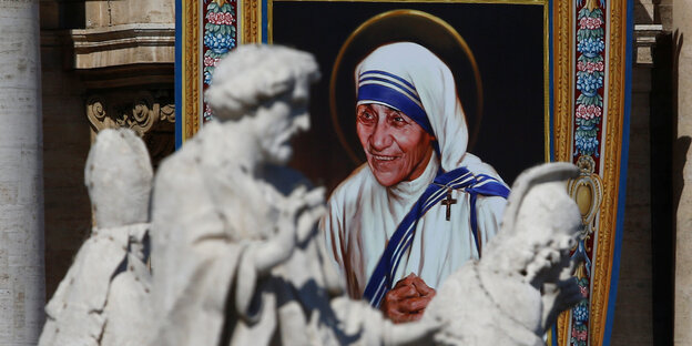 Ein Wandbild von Mutter Teresa hinter römischen Skulpturen Ein Wandbild von Mutter Teresa hinter römischen Skulpturen