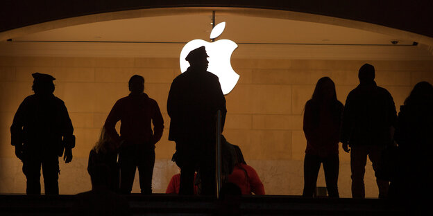 Silhouette mehrer Menschen vor dem Apple-Logo Silhouette mehrer Menschen vor dem Apple-Logo