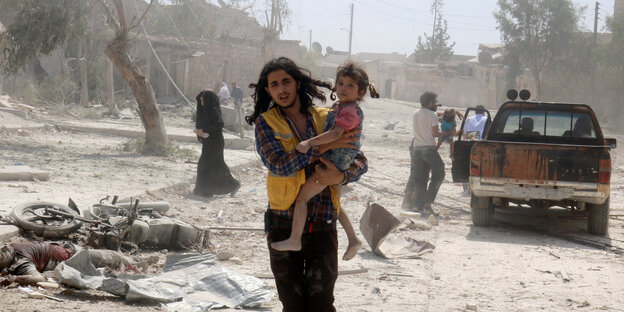 Mann mit Kind auf dem Arm im zerstörten Aleppo Mann mit Kind auf dem Arm im zerstörten Aleppo